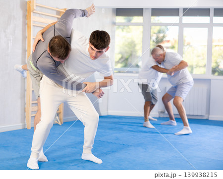 Young guy and man practice wrestling, apply techniques of Aikido and self-defense. Young guy and man practice wrestling, apply techniques of Aikido and self-defense. 139938215