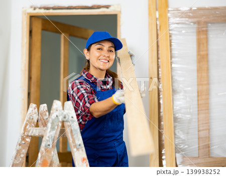 Cheerful female repairer carrying bunch of wooden planks Cheerful female repairer carrying bunch of wooden planks 139938252