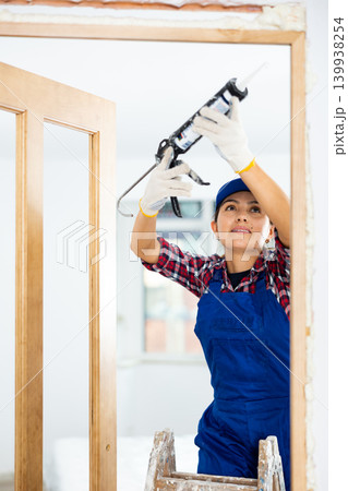 Female professional door installer fills gaps with mounting foam Female professional door installer fills gaps with mounting foam 139938254