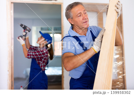 Man builder carrying wooden planks in construction site Man builder carrying wooden planks in construction site 139938302