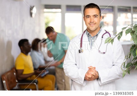 Young male doctor posing against the background of waiting room Young male doctor posing against the background of waiting room 139938305