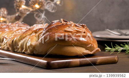 Homemade braided sweet Christmas bread with sliced almonds on a wooden board Homemade braided sweet Christmas bread with sliced almonds on a wooden board 139939562