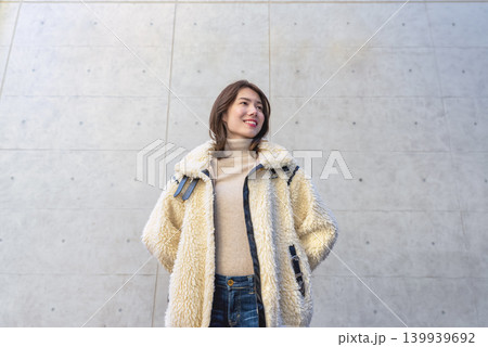 コンクリート壁の前で微笑む若い女性のポートレート 139939692