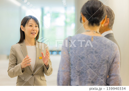 イベントホールに出かけるミドル夫婦を案内するスタッフ 139940334