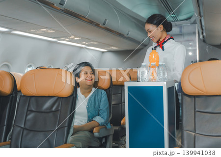 Flight attendant serving drink to smiling passenger in business class cabin Flight attendant serving drink to smiling passenger in business class cabin 139941038