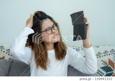 Asian woman trying to find money in her empty wallet. Having financial problems means being unable to pay debts over the short or long term. Asian woman trying to find money in her empty wallet. Having financial problems means being unable to pay debts over the short or long term. 139941331