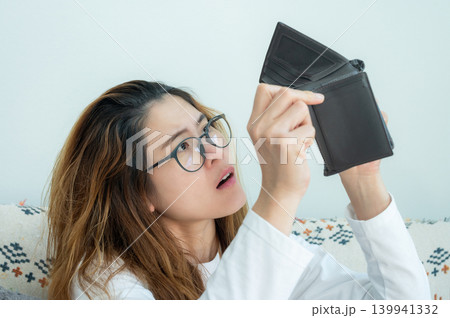 Asian woman trying to find money in her empty wallet. Having financial problems means being unable to pay debts over the short or long term. Asian woman trying to find money in her empty wallet. Having financial problems means being unable to pay debts over the short or long term. 139941332