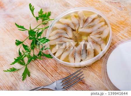 Pieces of salted herring fillet lie in oil-vinegar mixture with pickled onion, fish preserves Pieces of salted herring fillet lie in oil-vinegar mixture with pickled onion, fish preserves 139941644