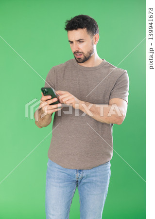 Adult man scrolling smartphone screen in front of green screen Adult man scrolling smartphone screen in front of green screen 139941678