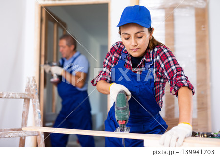 Woman carpenter using jigsaw in construction site Woman carpenter using jigsaw in construction site 139941703