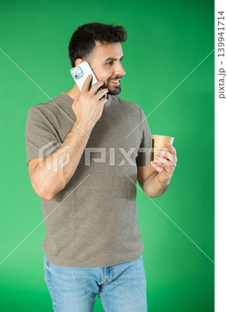 Man with cup of coffee is talking on phone, emotionally communicating with friend Man with cup of coffee is talking on phone, emotionally communicating with friend 139941714