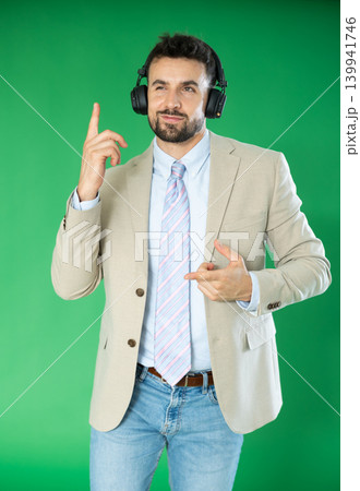 Adult man listening to music with headphones in front of green screen 139941746