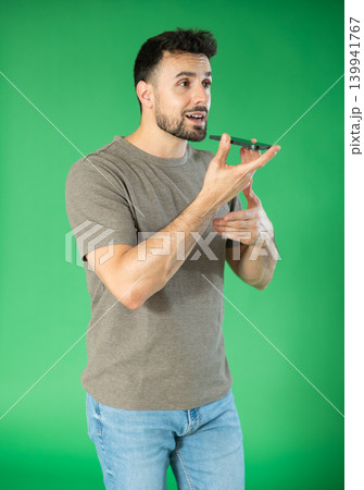 Adult man recording voice message in front of green screen 139941767