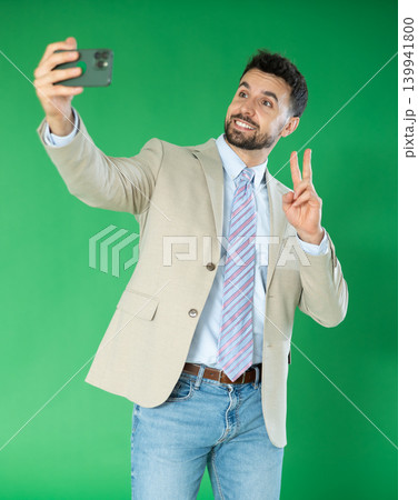 Happy adult man takes selfie on a green background. Chroma key compositing 139941800