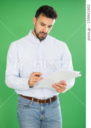 Adult man making notes on paper documents in front of green screen 139941802