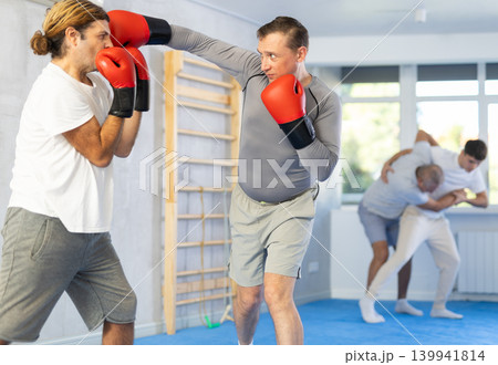 Men in boxing gloves punch deliver blow each other during training sparring session. 139941814