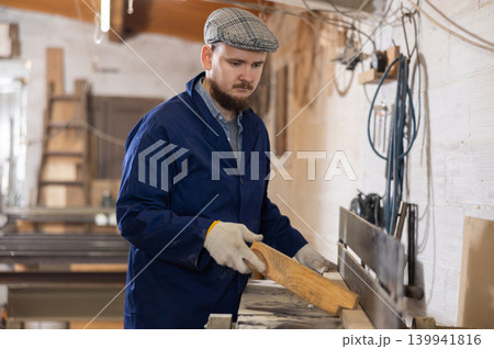 Young man working with wooden board on workbench Young man working with wooden board on workbench 139941816