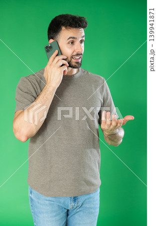 Adult man talking on mobile phone in front of green screen Adult man talking on mobile phone in front of green screen 139941871