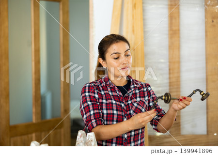 Woman fixing door handle in apartment Woman fixing door handle in apartment 139941896
