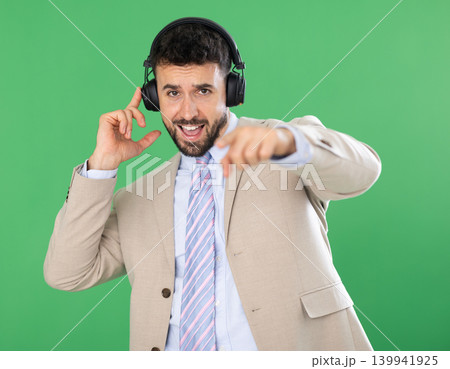 Adult man listening to music with headphones in front of green screen 139941925