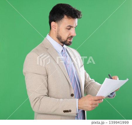 Adult man making notes on paper documents in front of green screen Adult man making notes on paper documents in front of green screen 139941999