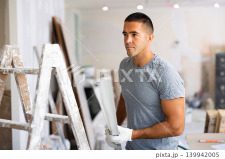 Young man holds an aluminum profile for interior decoration 139942005