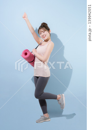 水色背景でヨガマットを持つ女性の健康的で美しいスポーツでトレーニングするジムやライフスタイル 水色背景でヨガマットを持つ女性の健康的で美しいスポーツでトレーニングするジムやライフスタイル 139942051