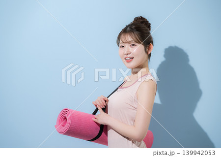 水色背景でヨガマットを持つ女性の健康的で美しいスポーツでトレーニングするジムやライフスタイル 139942053