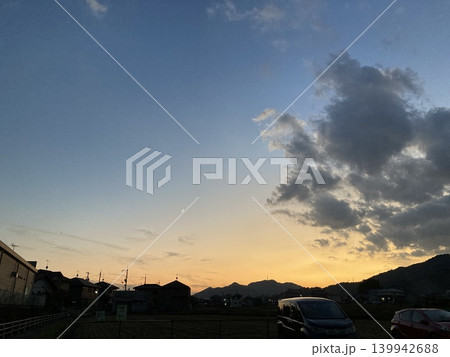 黄金色に輝く夕暮れ、伝統的な日本家屋のシルエットと田園風景 139942688