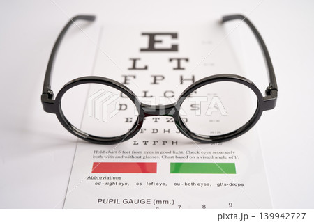 Glasses on eye testing exam chart to check eyesight accuracy of reading. Glasses on eye testing exam chart to check eyesight accuracy of reading. 139942727
