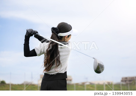 打ちっぱなしのゴルフ練習場でドライバーショットをスウィングする若い女性のゴルファーのスポーツイメージ 打ちっぱなしのゴルフ練習場でドライバーショットをスウィングする若い女性のゴルファーのスポーツイメージ 139943055