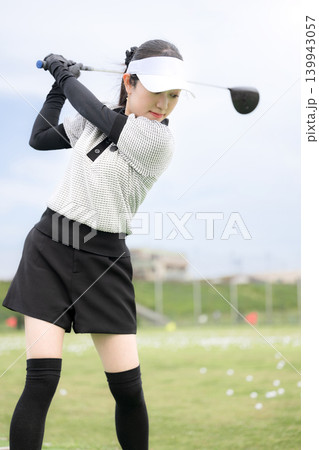 打ちっぱなしのゴルフ練習場でドライバーショットをスウィングする若い女性のゴルファーのスポーツイメージ 打ちっぱなしのゴルフ練習場でドライバーショットをスウィングする若い女性のゴルファーのスポーツイメージ 139943057