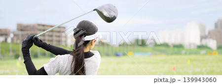 打ちっぱなしのゴルフ練習場でドライバーショットをスウィングする若い女性のゴルファーのスポーツイメージ 139943060