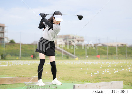 打ちっぱなしのゴルフ練習場でドライバーショットをスウィングする若い女性のゴルファーのスポーツイメージ 打ちっぱなしのゴルフ練習場でドライバーショットをスウィングする若い女性のゴルファーのスポーツイメージ 139943061
