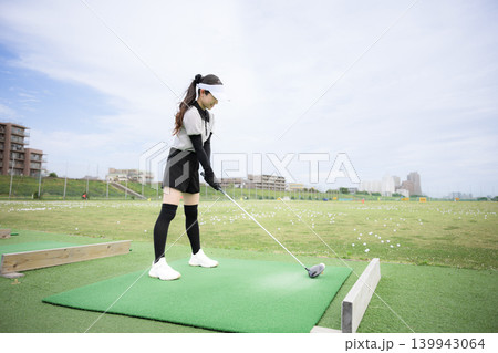 打ちっぱなしのゴルフ練習場でドライバーショットをスウィングする若い女性のゴルファーのスポーツイメージ 打ちっぱなしのゴルフ練習場でドライバーショットをスウィングする若い女性のゴルファーのスポーツイメージ 139943064