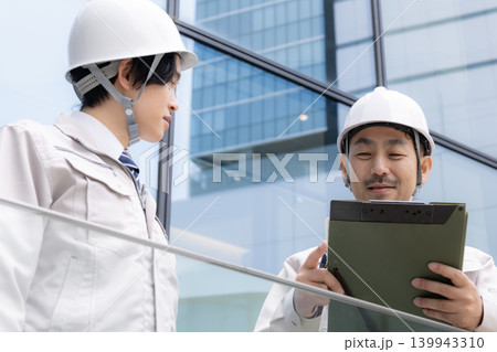 都会のビル背景の建設現場で若手技術者と現場監督が連携する成長イメージ動画 ojtやゼネコンなどの施工 都会のビル背景の建設現場で若手技術者と現場監督が連携する成長イメージ動画 ojtやゼネコンなどの施工 139943310
