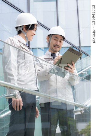 都会のビル背景の建設現場で若手技術者と現場監督が連携する成長イメージ動画　ojtやゼネコンなどの施工 139943312