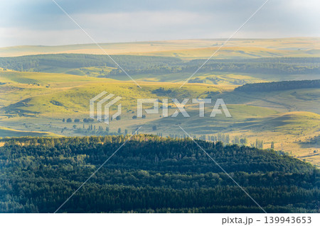 Layers of green mountains and hills in the haze during sunset. Panoramic View of Green hills and Meadow. 139943653