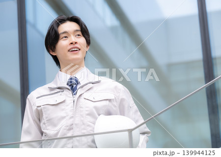 都会のビル背景で笑顔を見せる若手男性技術者と建設キャリアイメージ 就活やキャリアと成長、チャレンジ 都会のビル背景で笑顔を見せる若手男性技術者と建設キャリアイメージ 就活やキャリアと成長、チャレンジ 139944125