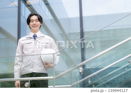 都会のビル背景で笑顔を見せる若手男性技術者と建設キャリアイメージ 就活やキャリアと成長、チャレンジ 都会のビル背景で笑顔を見せる若手男性技術者と建設キャリアイメージ 就活やキャリアと成長、チャレンジ 139944127