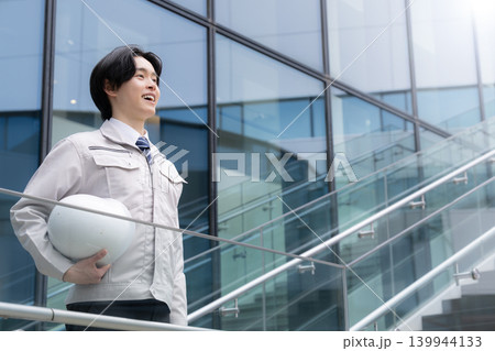 都会のビル背景で笑顔を見せる若手男性技術者と建設キャリアイメージ　就活やキャリアと成長、チャレンジ 139944133