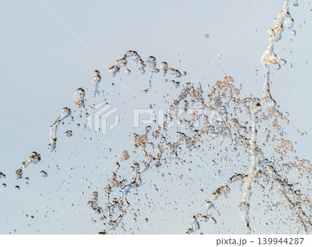 Splashes and jets of water against light background. Splashes and jets of water against light background. 139944287
