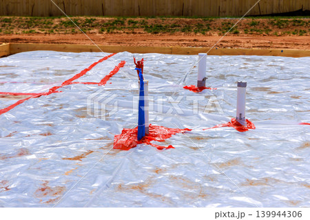 Construction site slab foundation work with plastic covering wooden frames 139944306