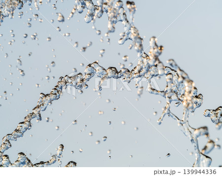 Splashes and jets of water against light background. Splashes and jets of water against light background. 139944336