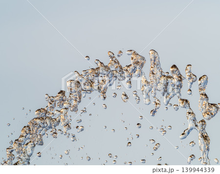 Splashes and jets of water against light background. Splashes and jets of water against light background. 139944339