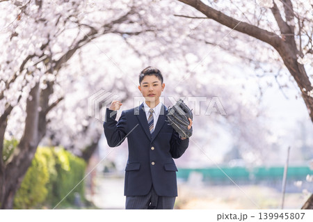 満開の桜の下でグローブを付けた男子高校生 139945807