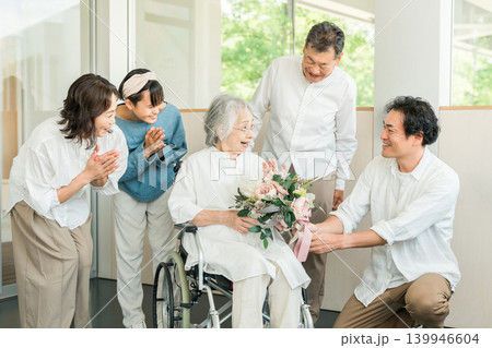施設にいるおばあちゃんにお見舞い,お祝いで花束をプレゼントする三世代家族 施設にいるおばあちゃんにお見舞い,お祝いで花束をプレゼントする三世代家族 139946604