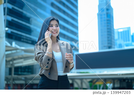 Businesswoman talking on smartphone in business district Businesswoman talking on smartphone in business district 139947203