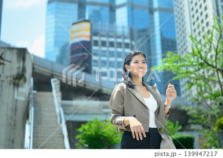 Confident businesswoman smiling outdoors in modern city Confident businesswoman smiling outdoors in modern city 139947217