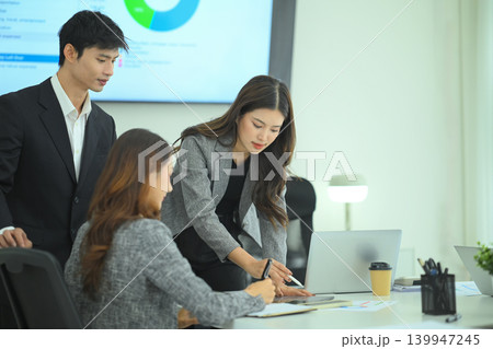 Three business professionals reviewing tablet data and reports during strategic meeting in modern office Three business professionals reviewing tablet data and reports during strategic meeting in modern office 139947245